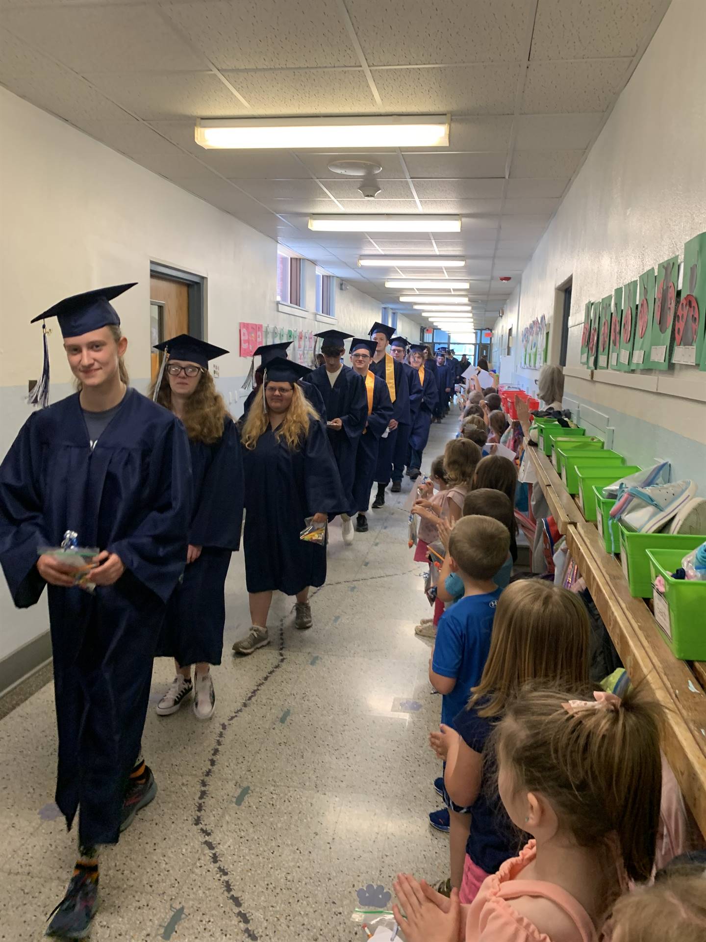 high school graduates walk through halls of their primary school