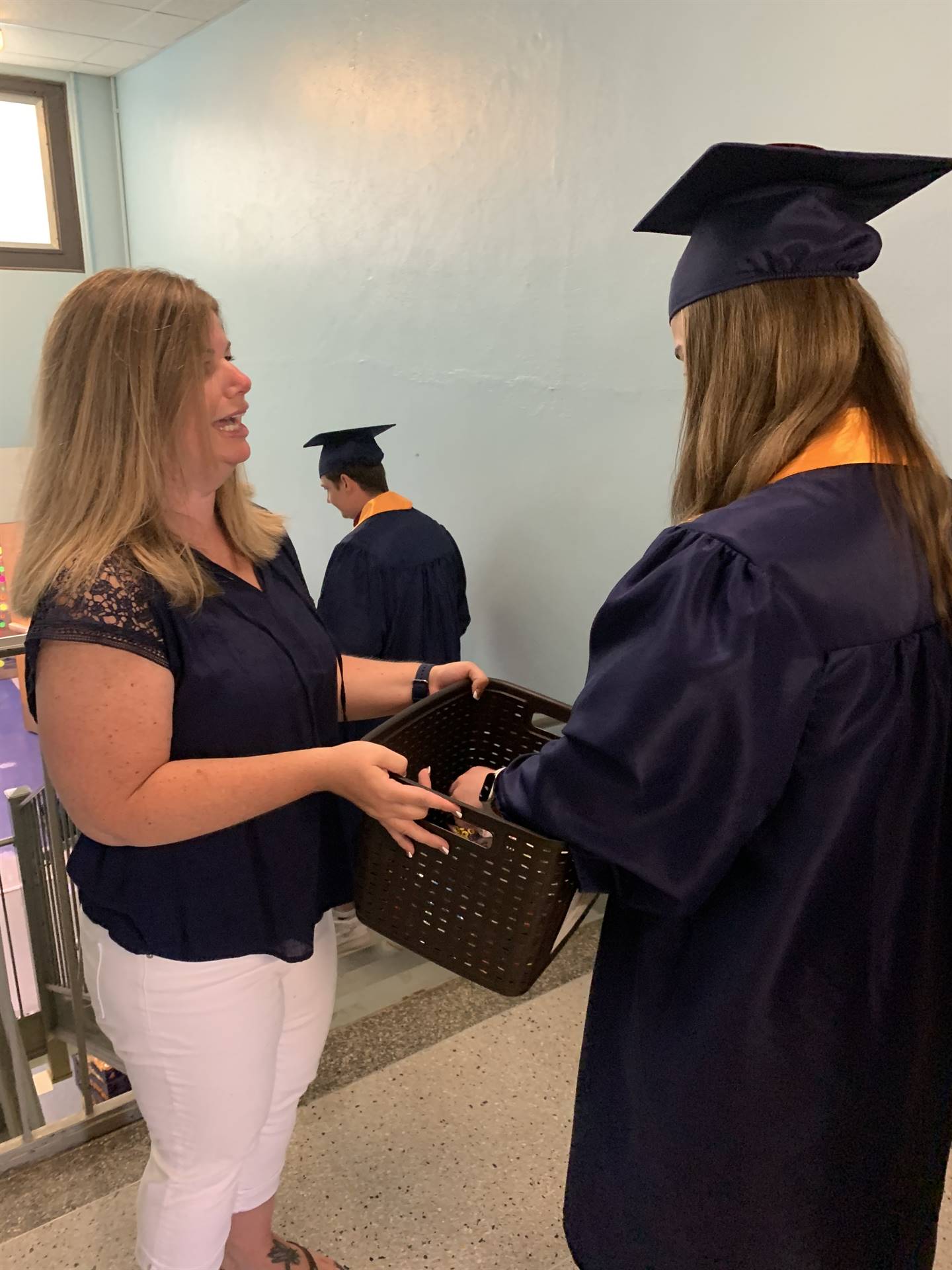 high school graduate takes a survival kit from a primary teacher
