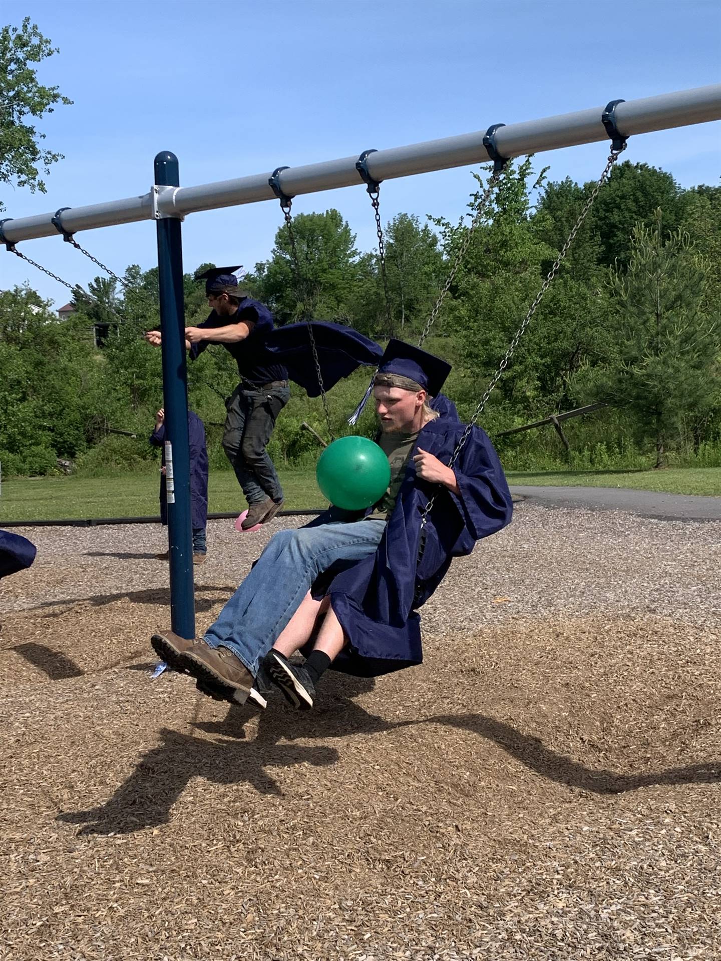 a high school graduate swings with balloon in hand