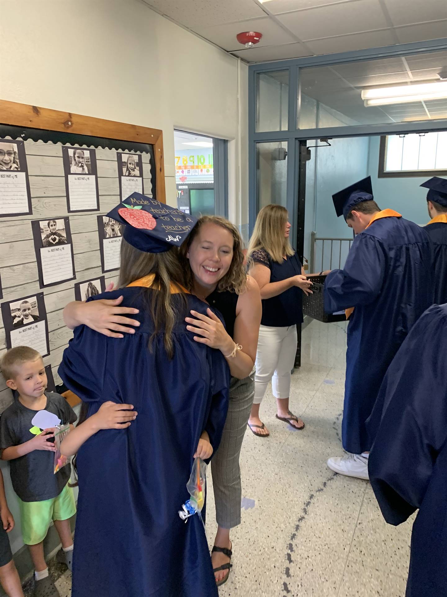 a high school graduate hugs her former teacher