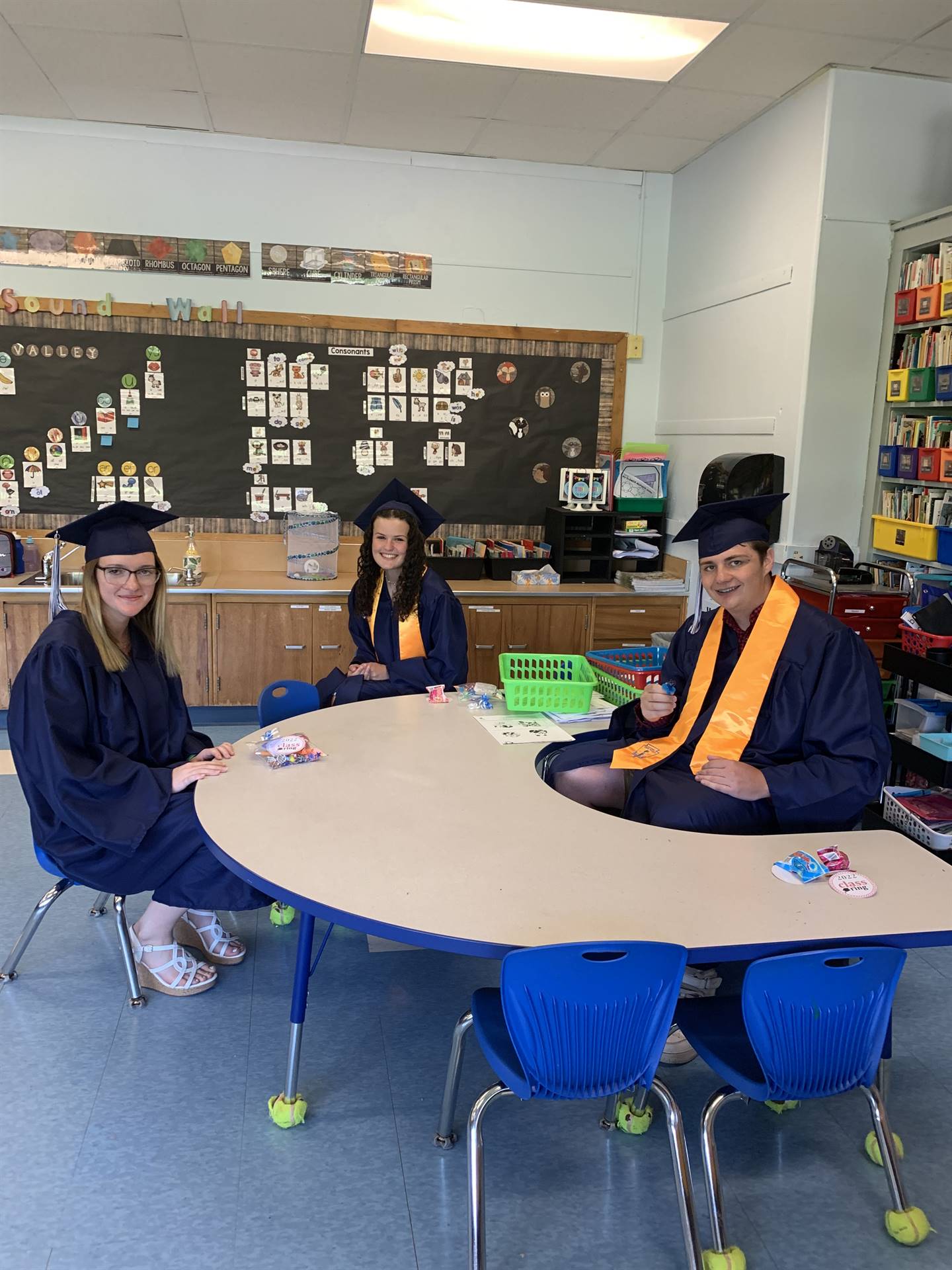 3 high school graduates sit at a primary table