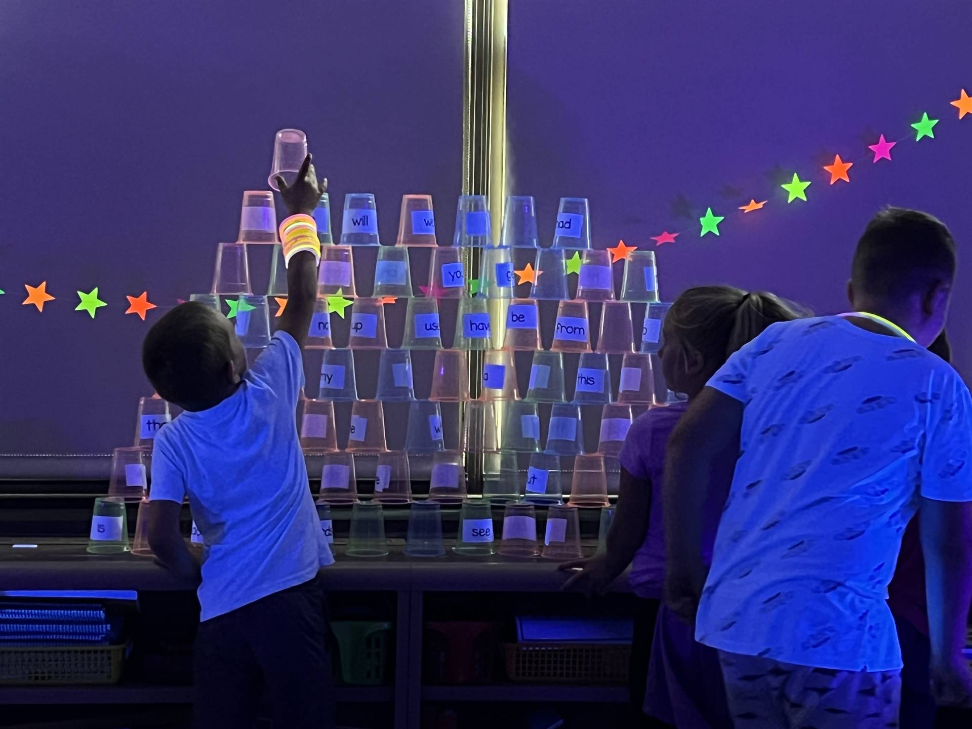 students work together to create a glow day pyramid from cups