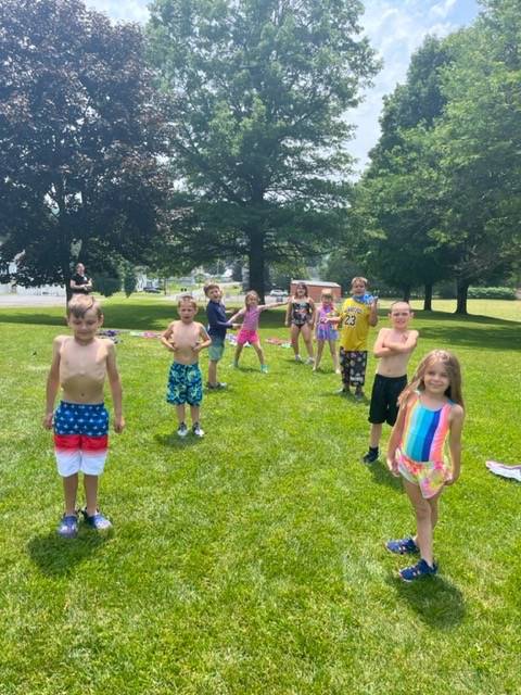 a group of students dressed in beach attire outdoors throwing water balloons