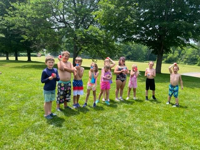 a group of students dressed in beach attire outdoors throwing water balloons
