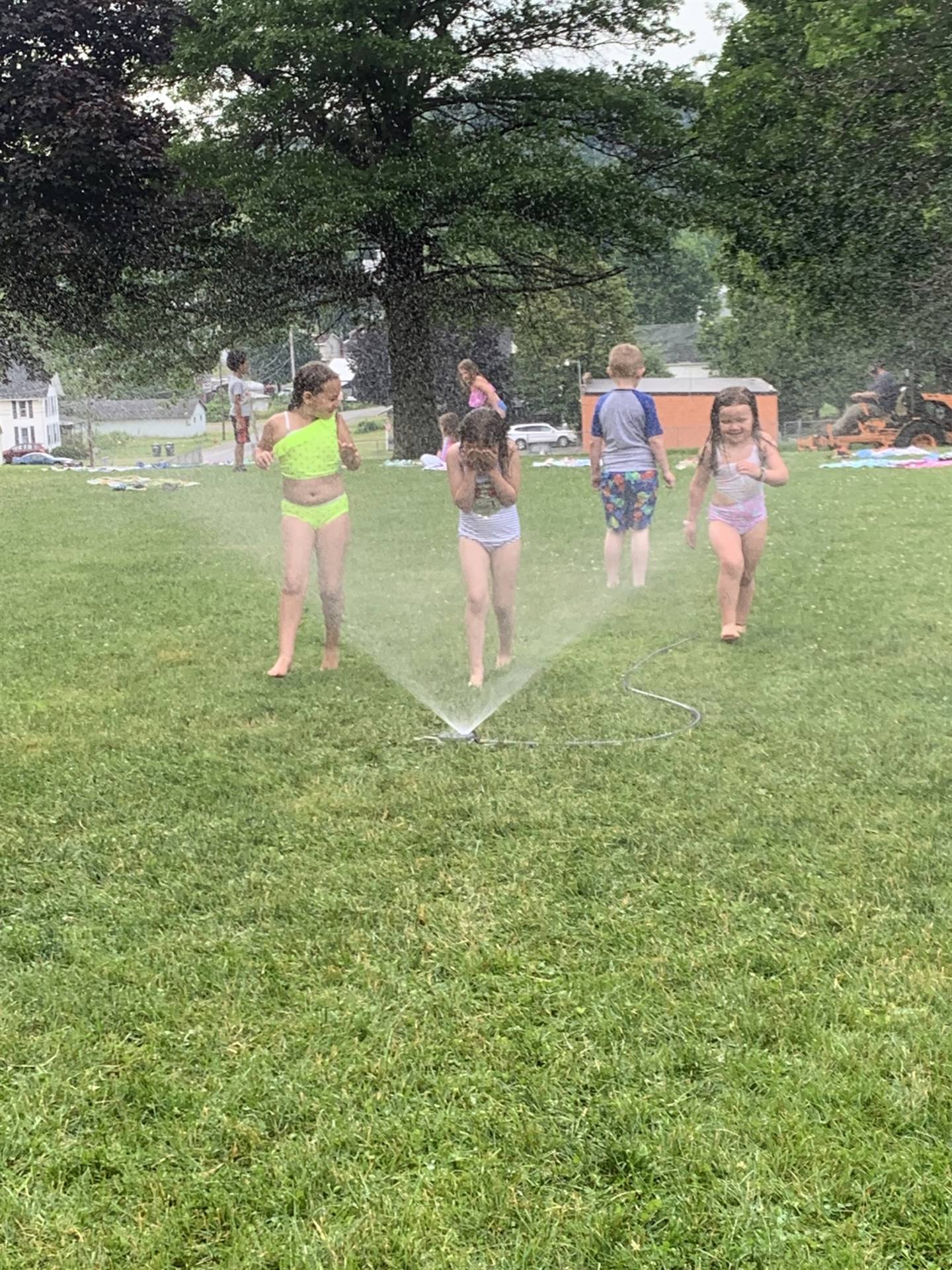 students running under a sprinkler