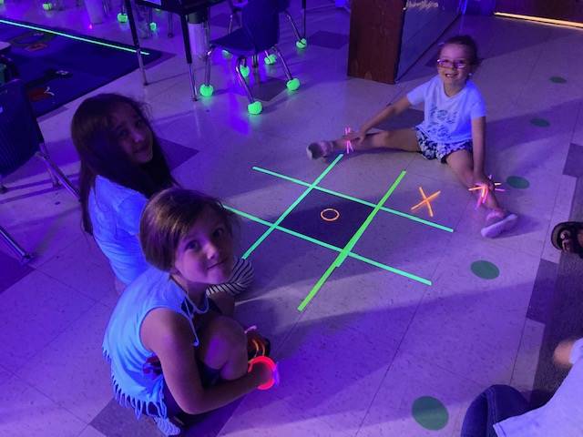 3 students playing a glow day tic tac toe