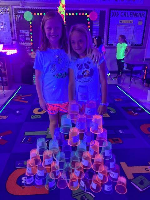 2 students showing off their glow day cup pyramid
