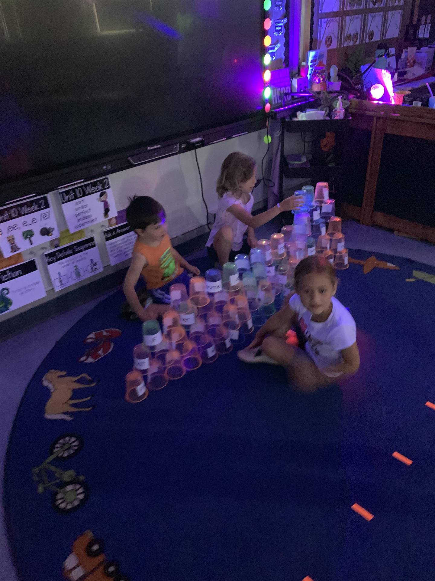 3 kids using cooperation with glow cups to make a pyramid
