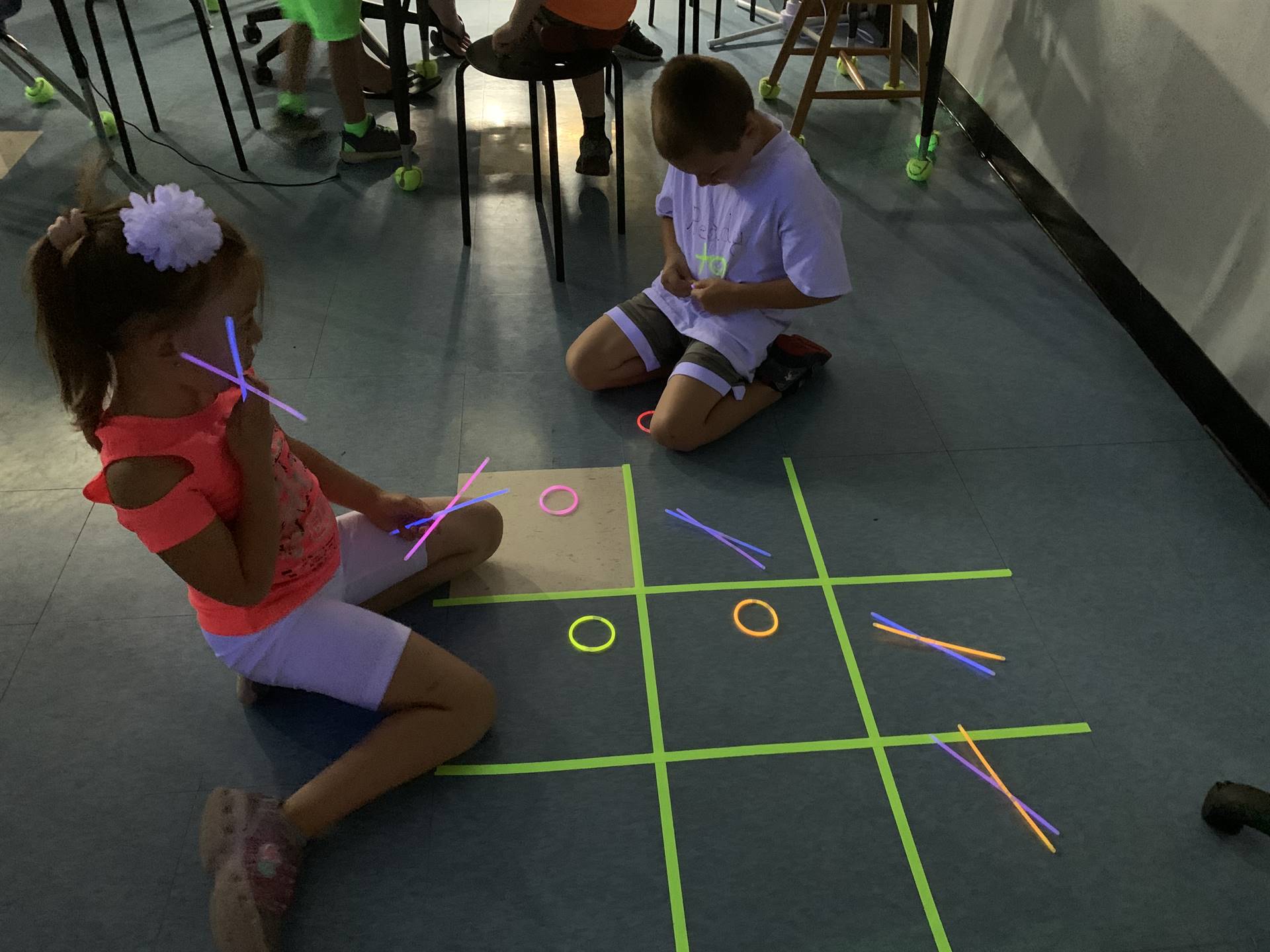 2 students playing glow day tic tac toe