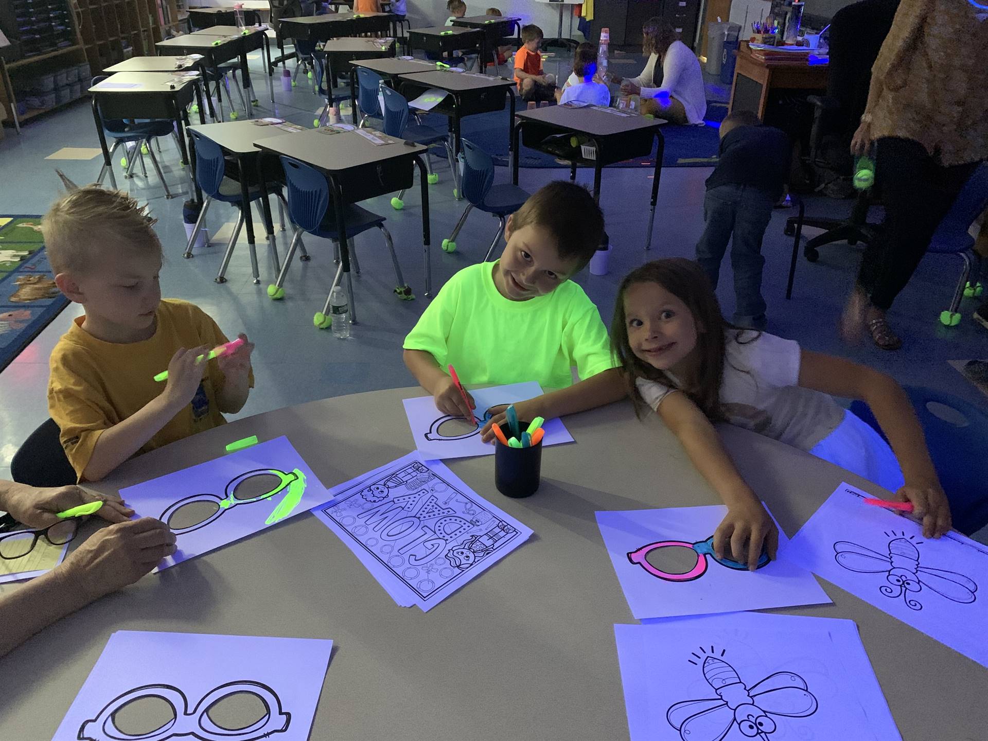 3 students color glow day pictures with markers