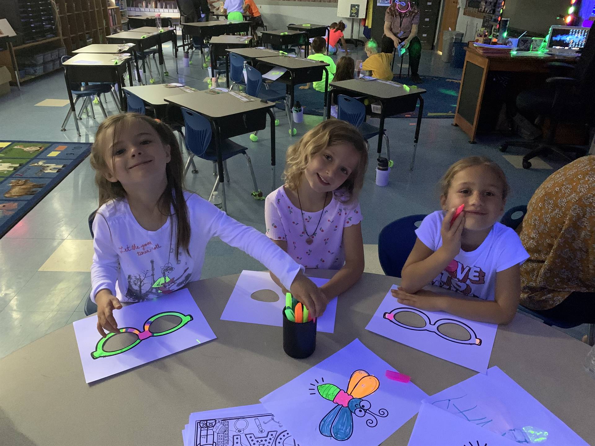 3 students color glow day pictures with markers