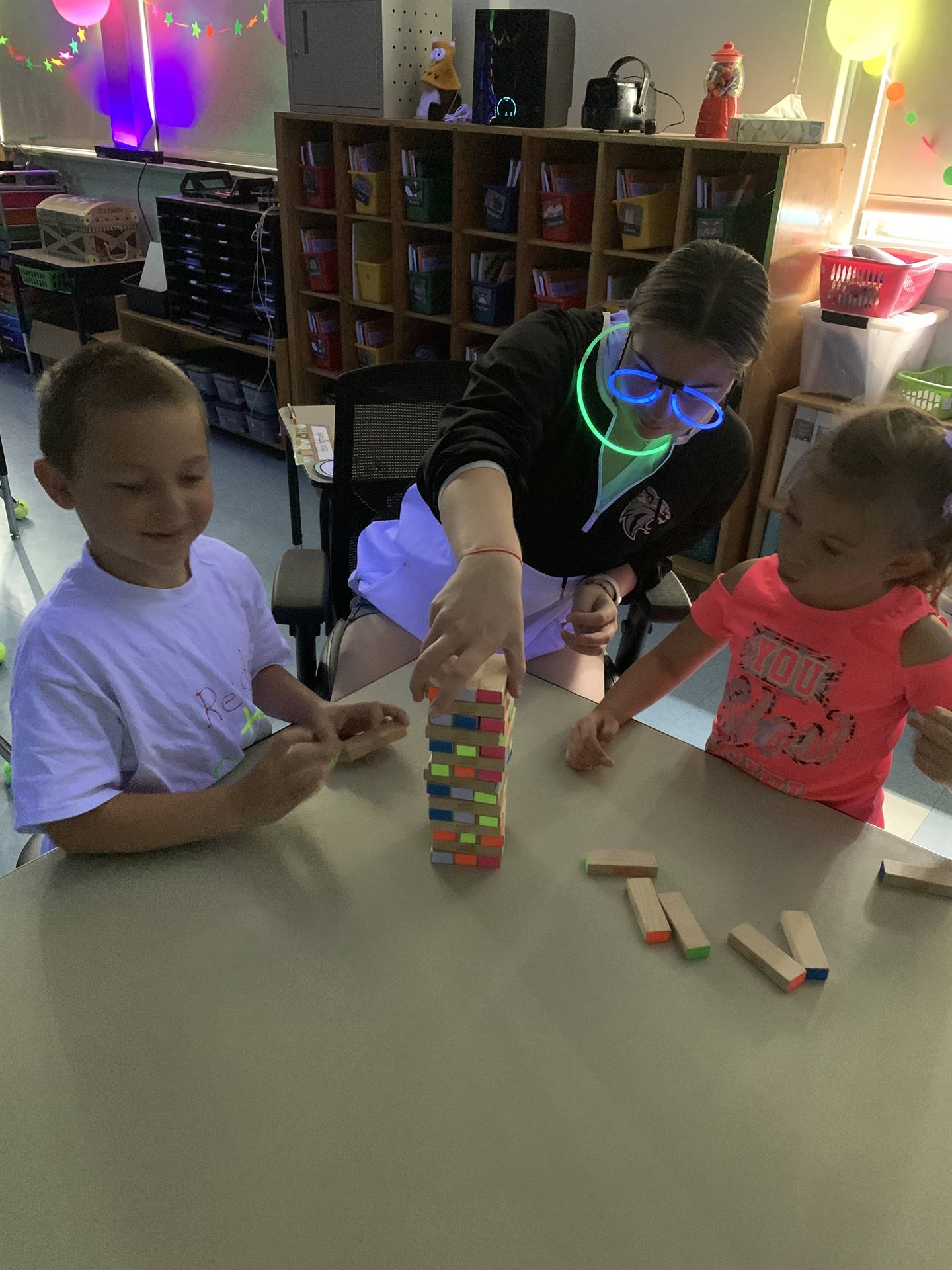 students and a staff helper play glow day jenga