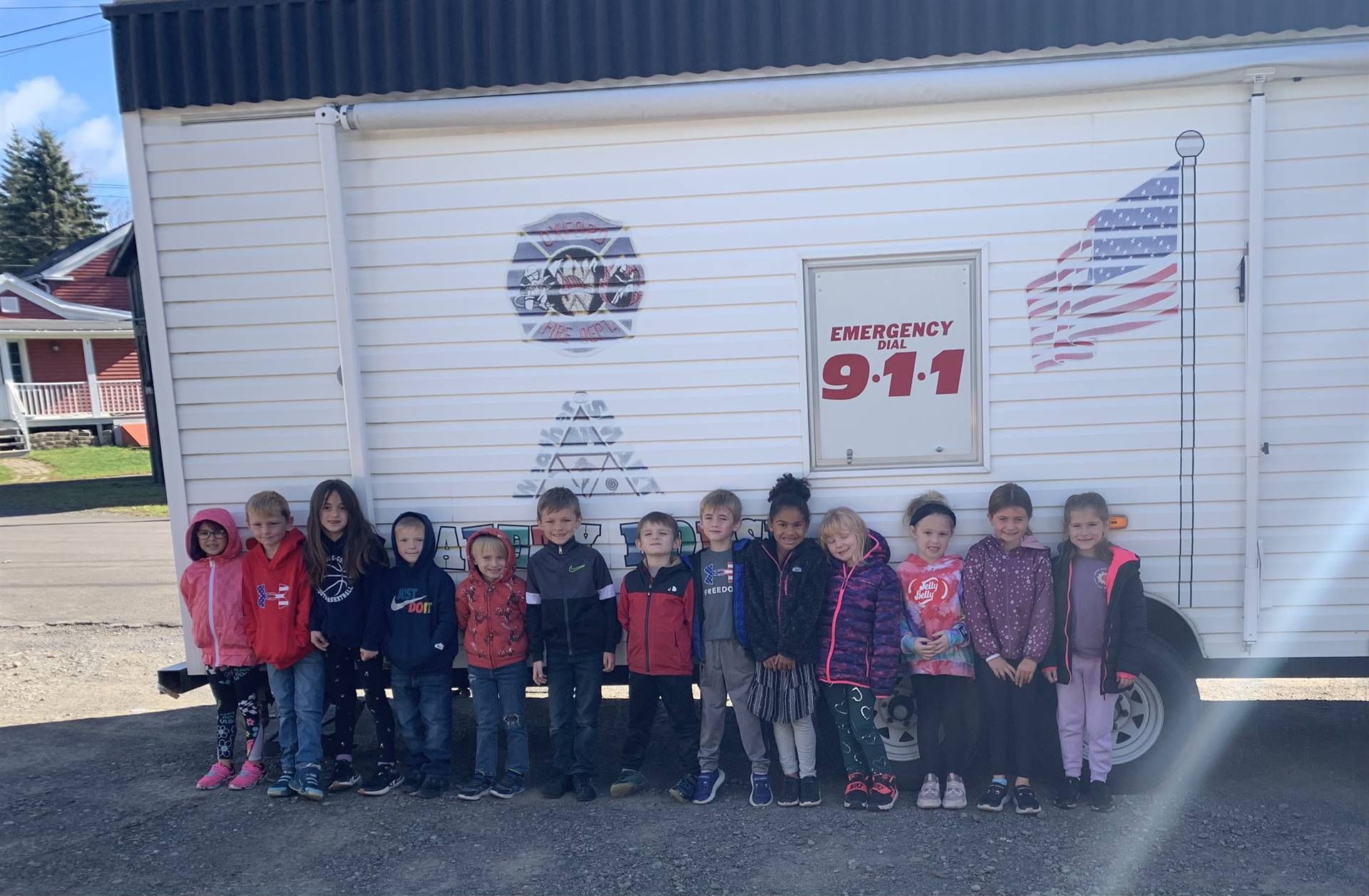 students in front of fire safety trailer. American Flag and 911  painted on trailer