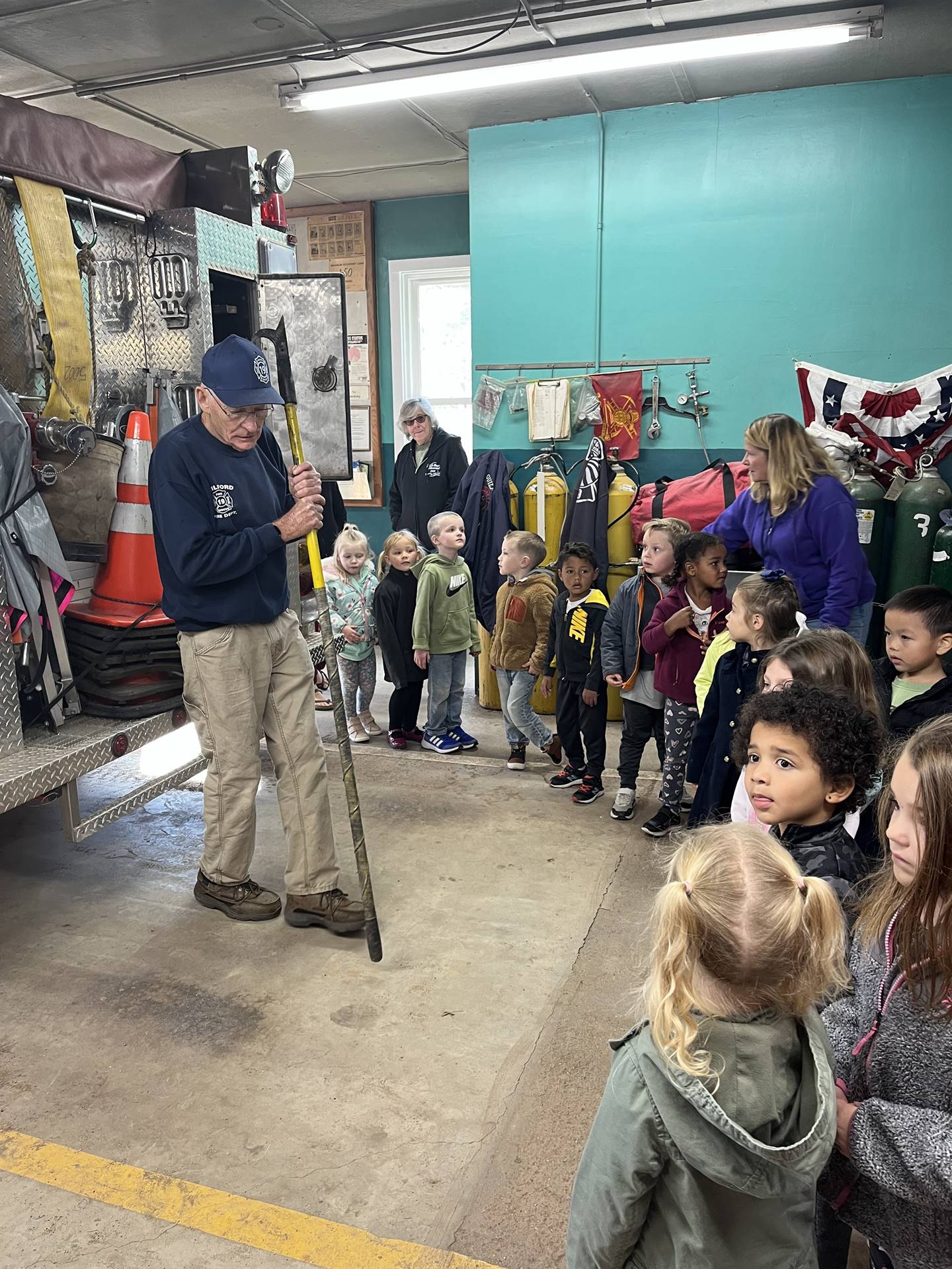 students listen to a firefighter explain how they poke through ceilings to find fires.