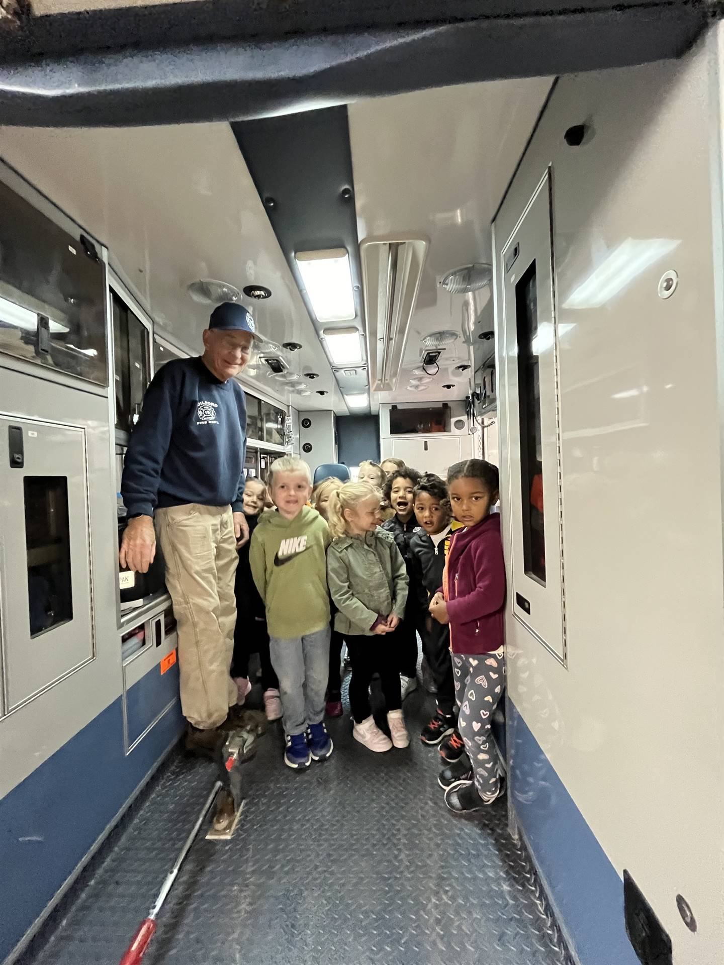 firefighter shows the inside of an ambulance to students.