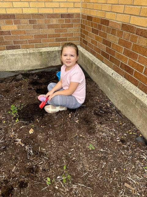 A student sitting in a garden outside.