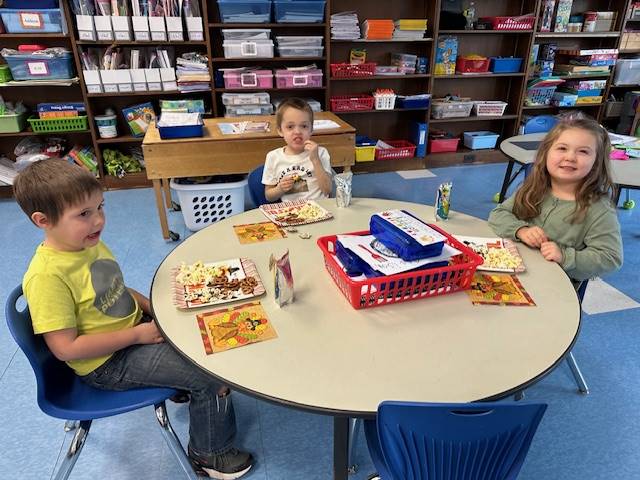 3 students at a table sampling different foods