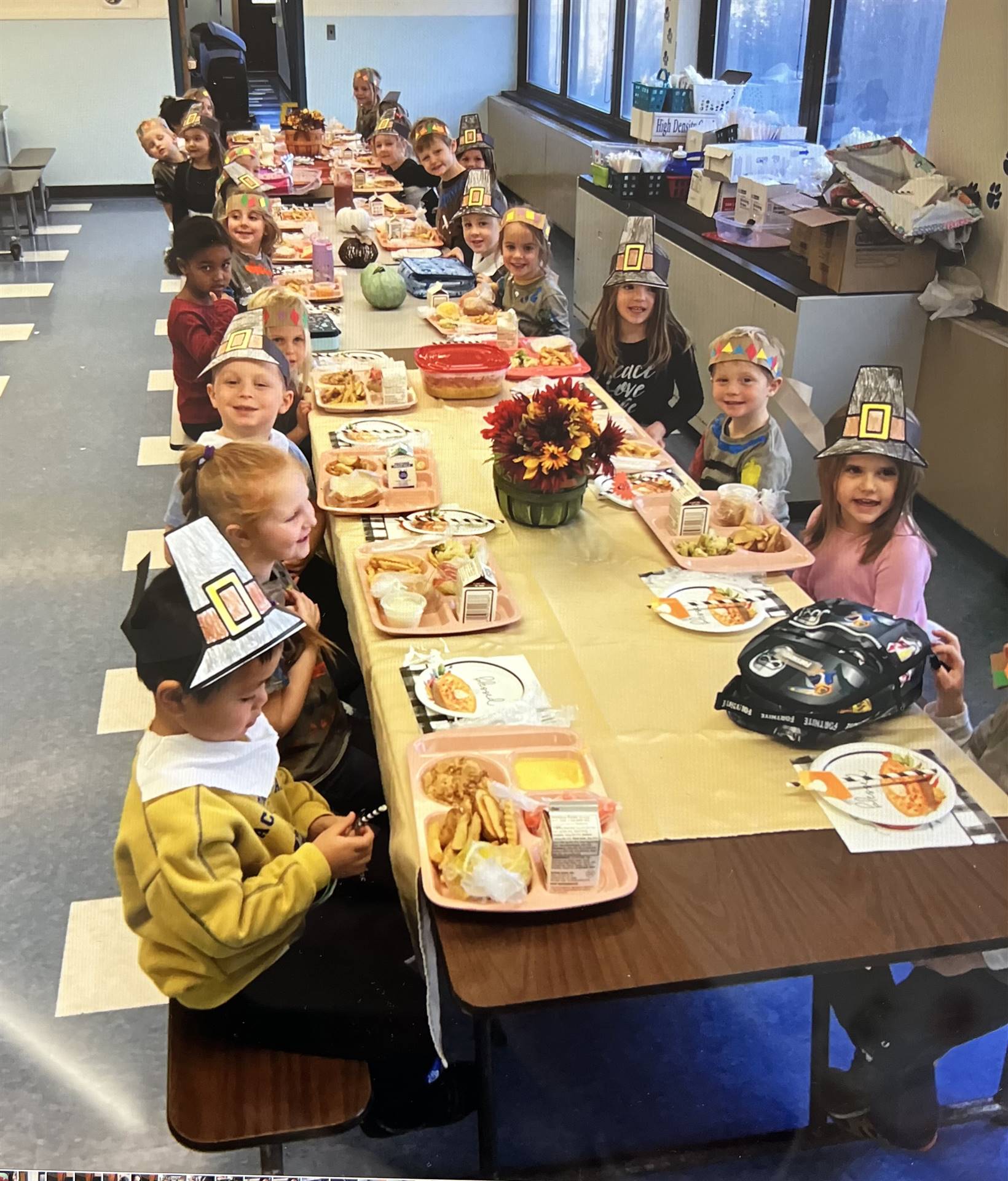 a group of students at a table with hats on and plates of food.