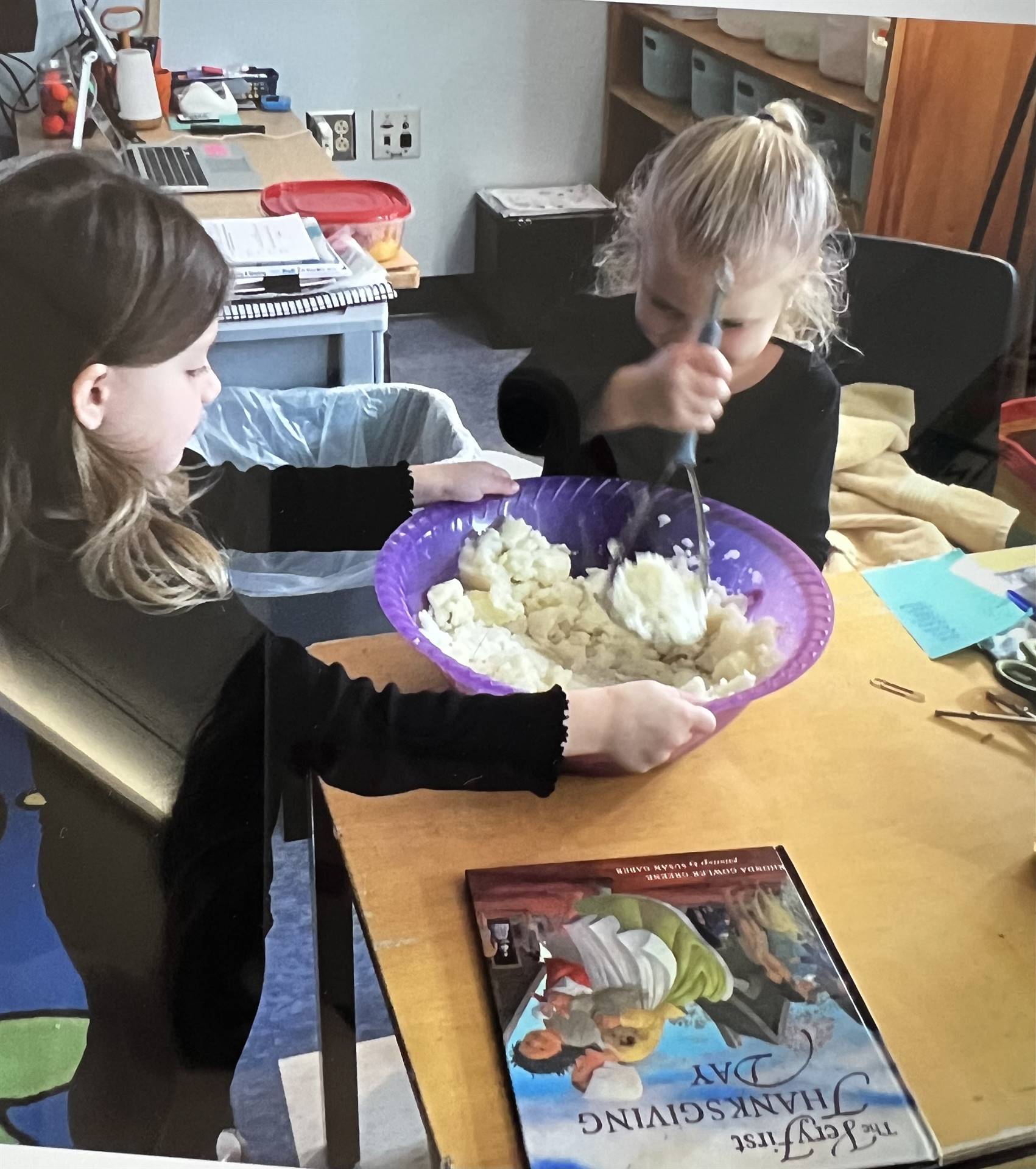 2 students take a scoop of mashed potatoes from a bow.