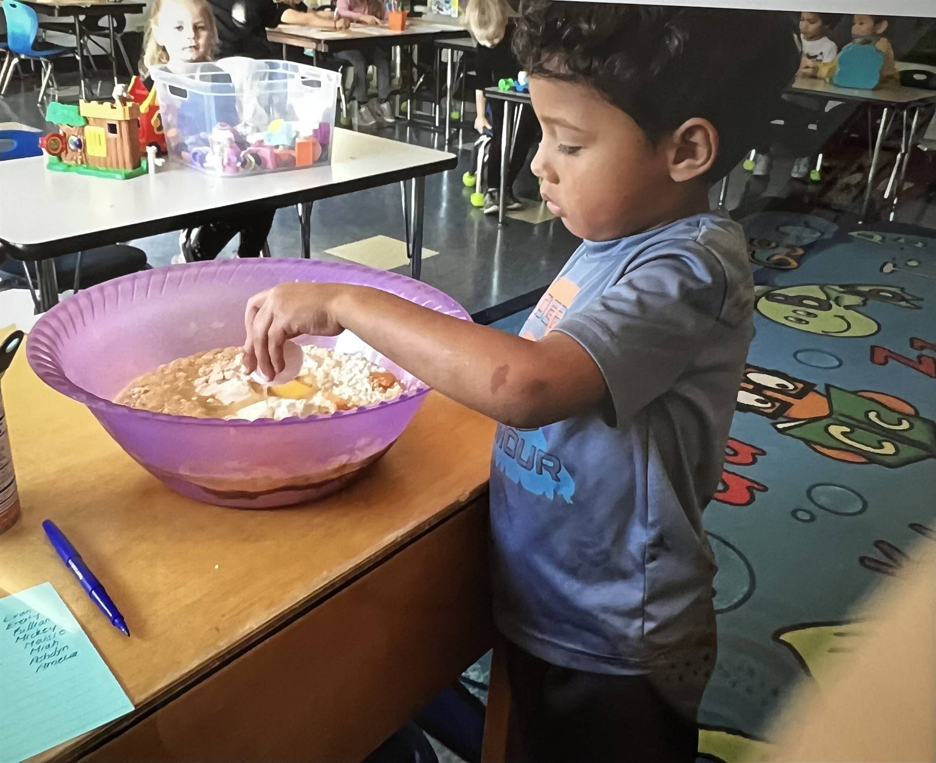 a student puts ingredients into a bowl for a batter.