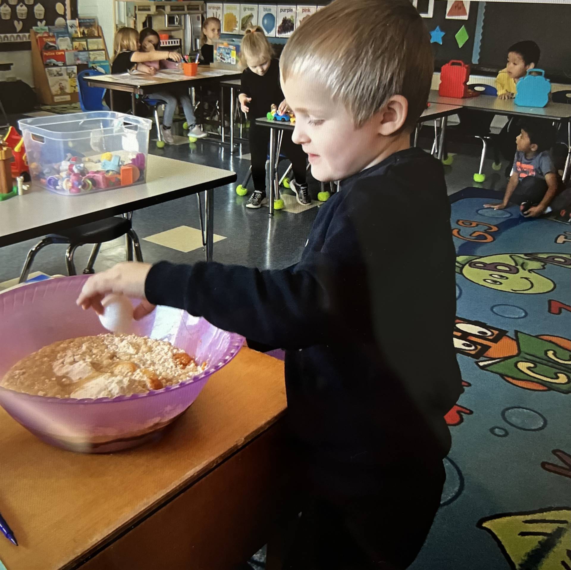 a student cracks an egg into a bowl for a batter.