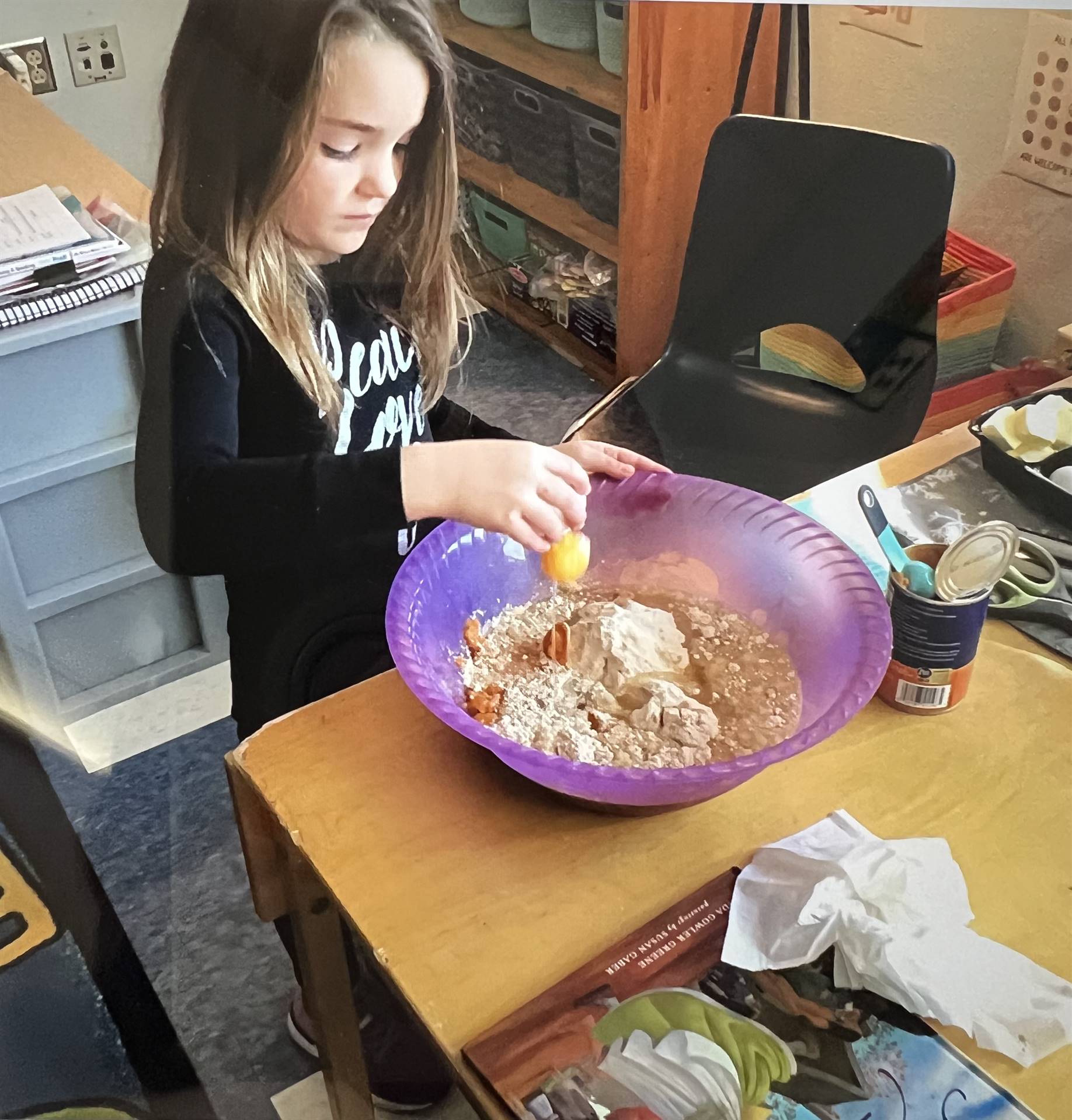 a student cracks an egg into a bowl for a batter.