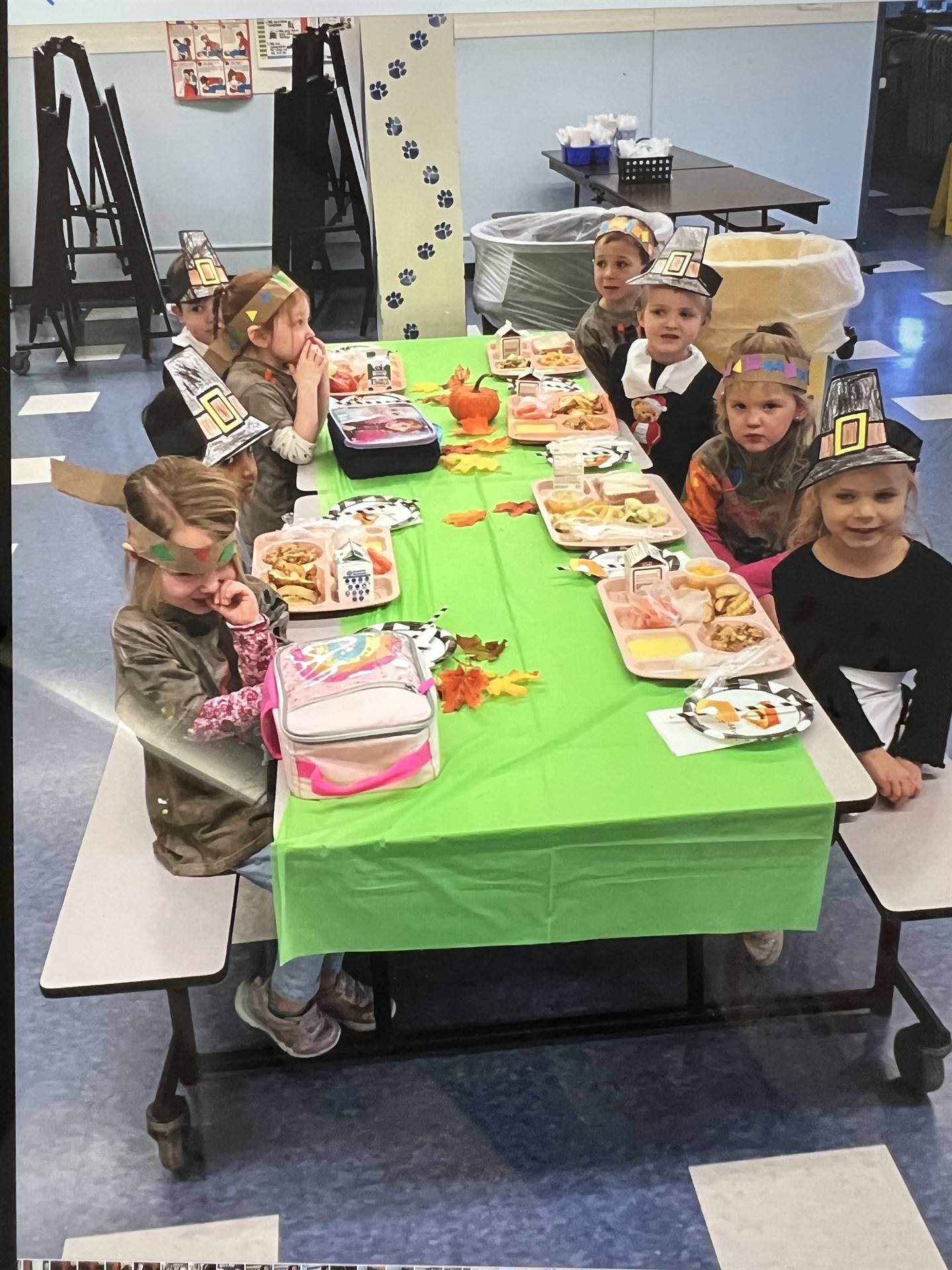 a group of students at a table with hats on and plates of food.