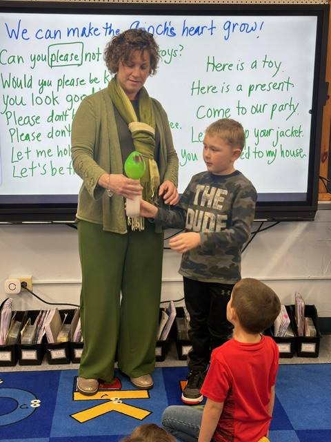 adult holding bottle with green balloon on top while student watches balloon get bigger.