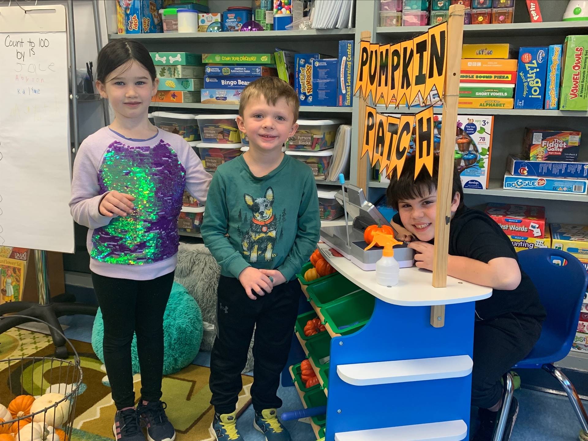 3 students buddy up to play in the play pumpkin patch.