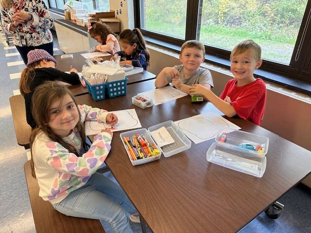 students eat food off a play and wear paper chef hats.