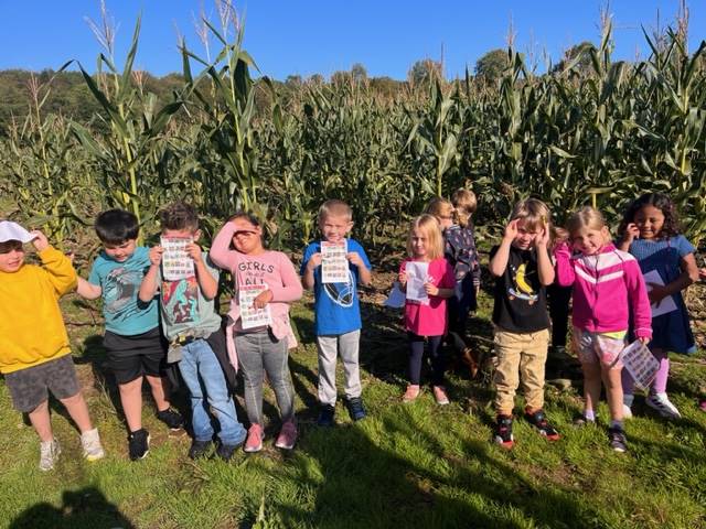 a group of students stand in front of a corn field.