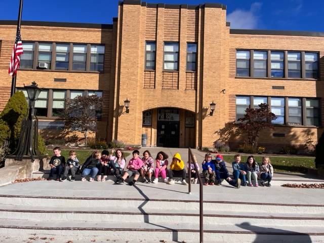 a group of students sitting on steps in front of Guilford elementary school