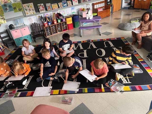 a group of students sitting on floor with books to write in.