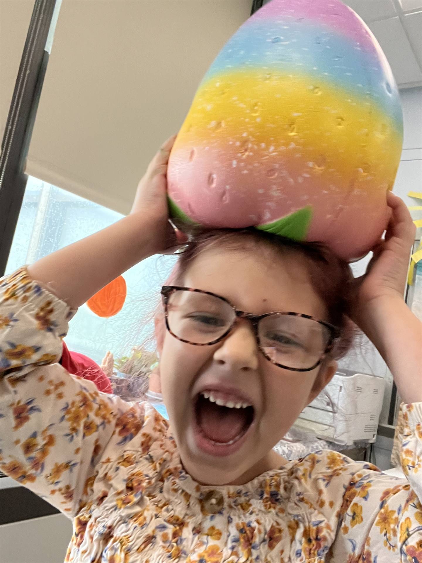 child with giant rainbow strawberry on head