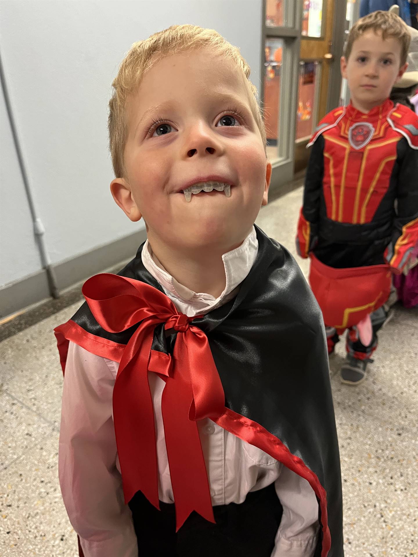 a student smiles big vampire teeth for halloween