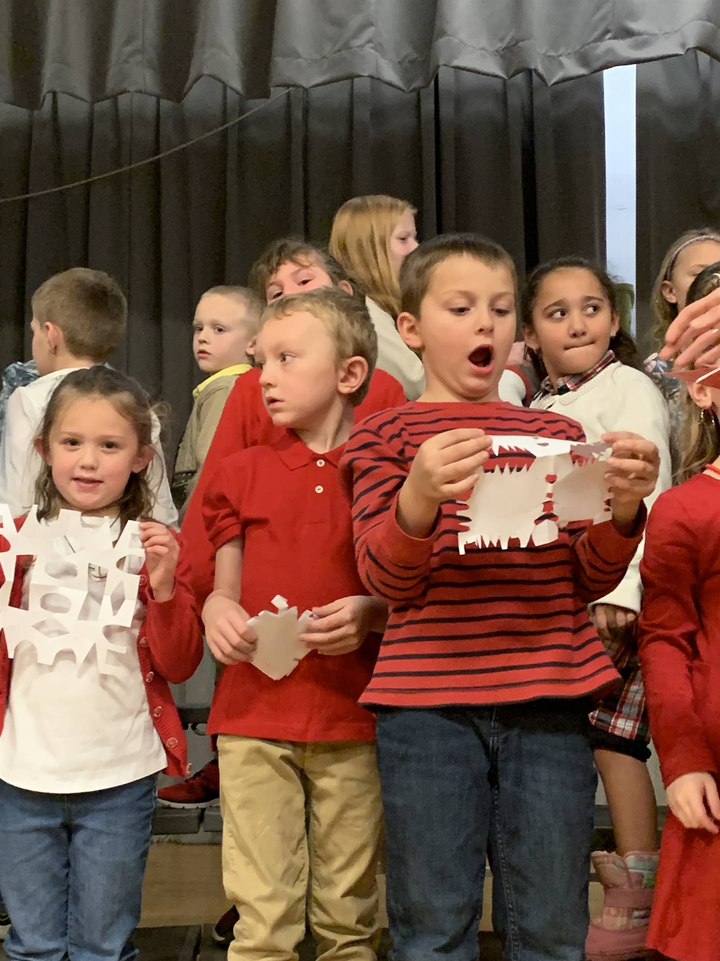 students singing while holding paper snowflakes