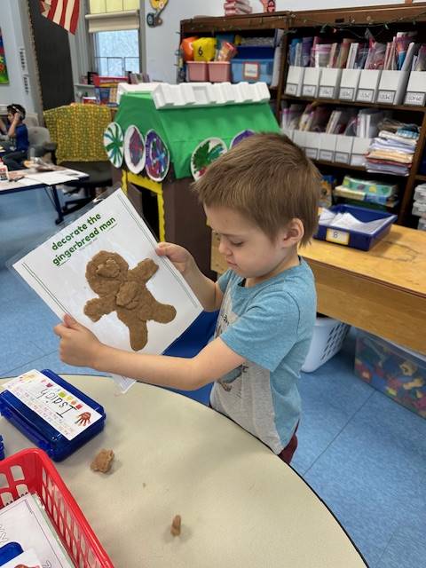 A students holds up a play do  gingerbread friend he created!