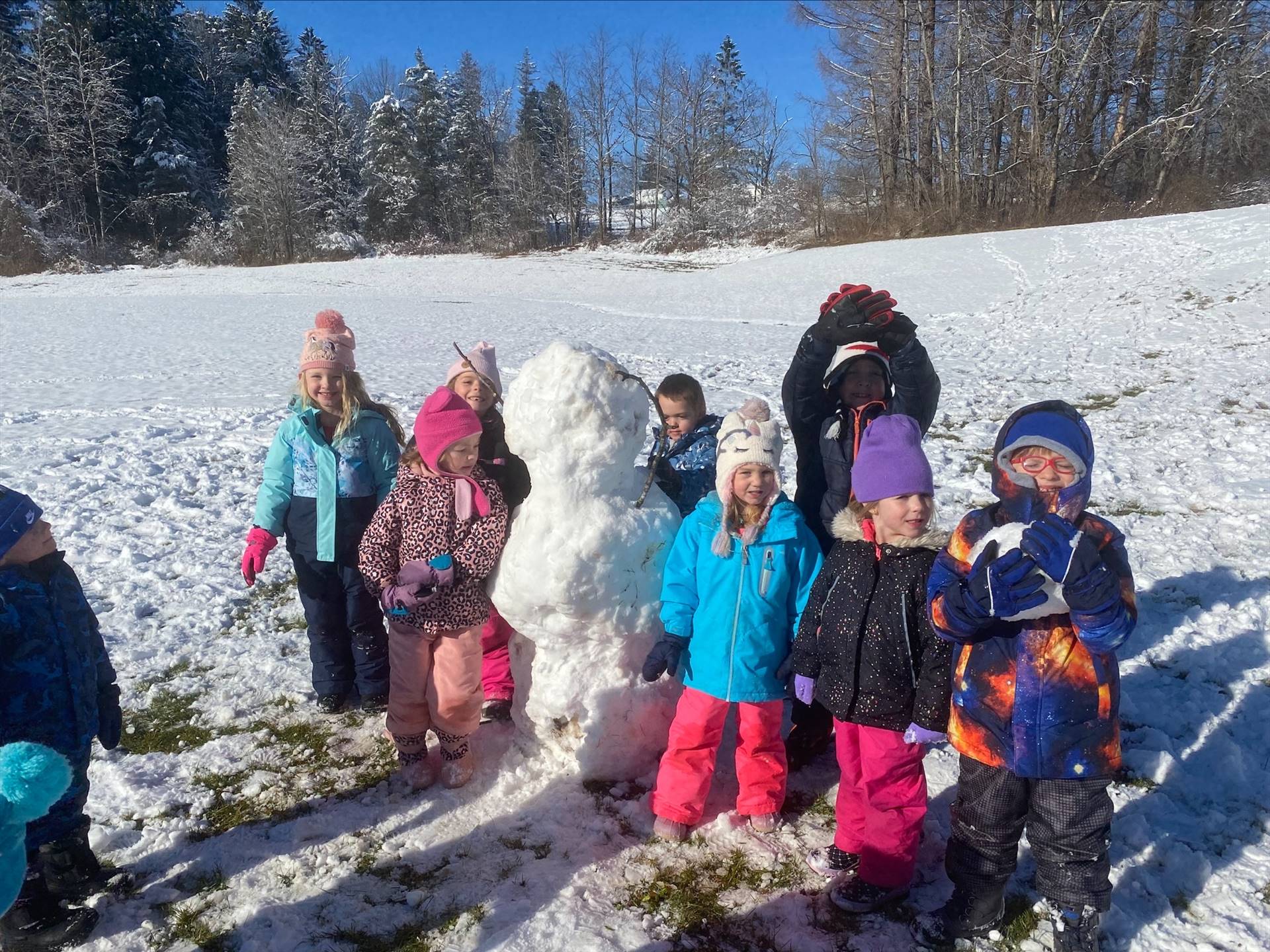 group of students outdoors with a giant snowman in middle.