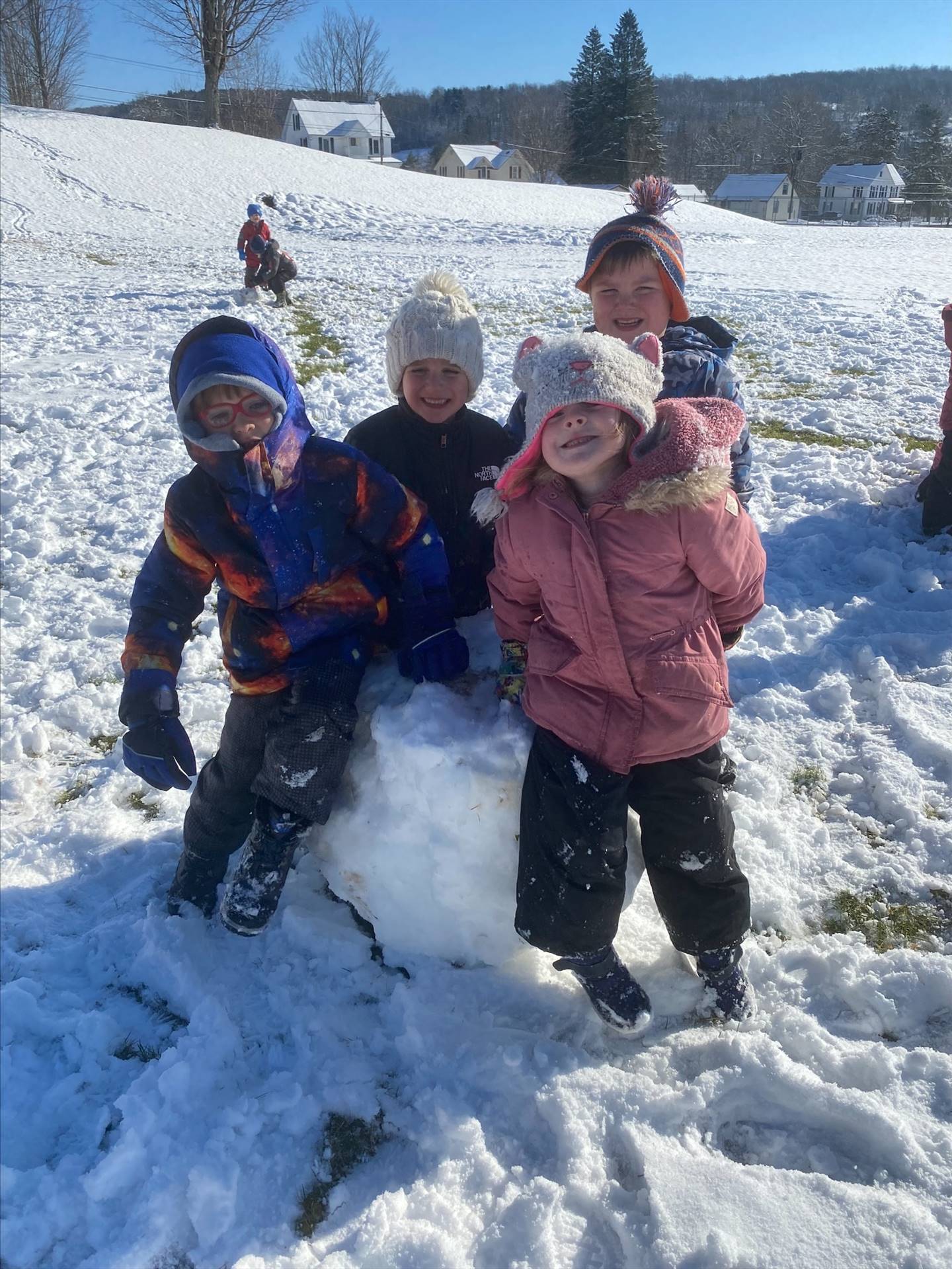 4 students outdoors sitting on a giant snowball