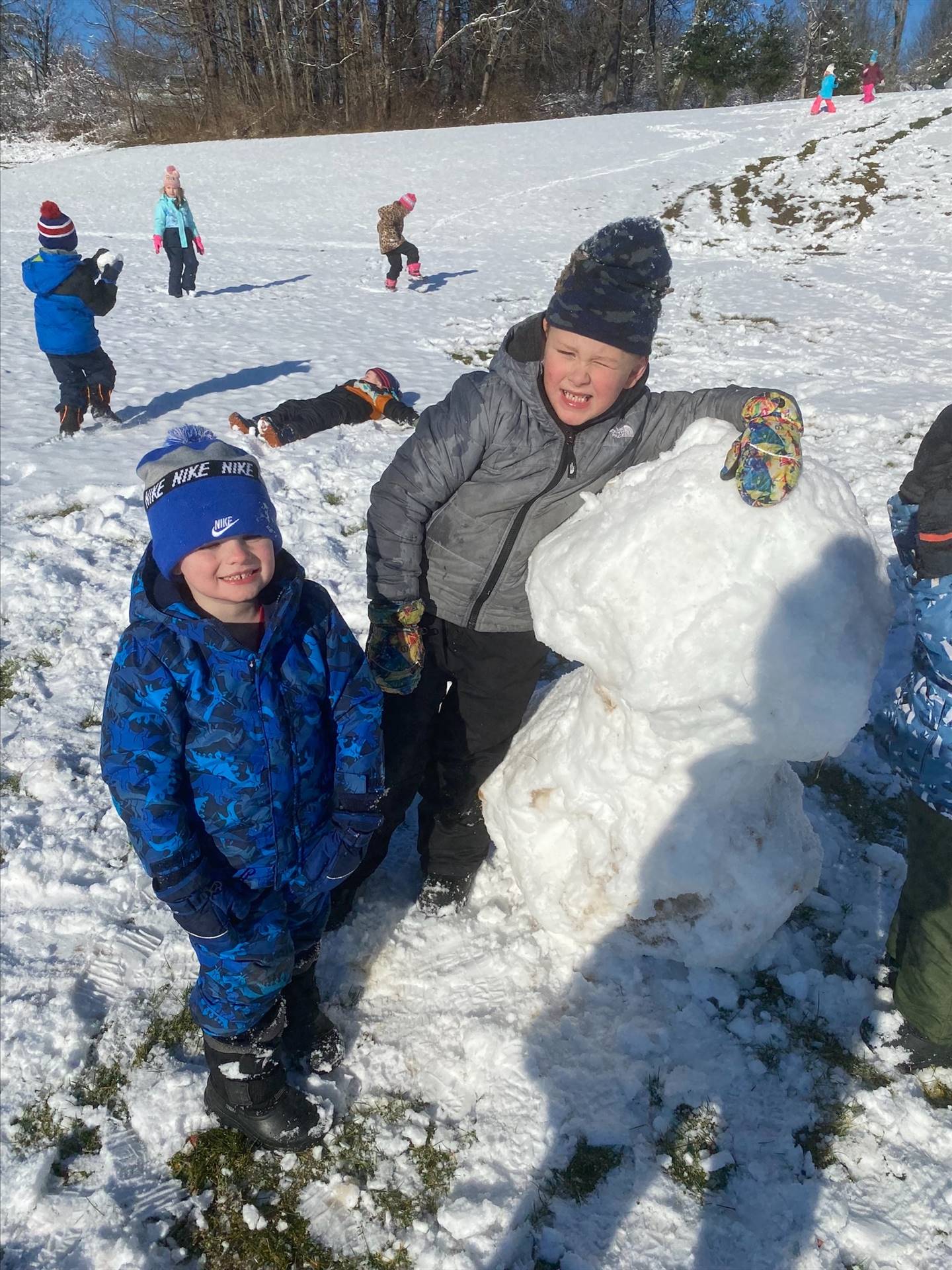 2 students outdoors sitting on a giant snowball