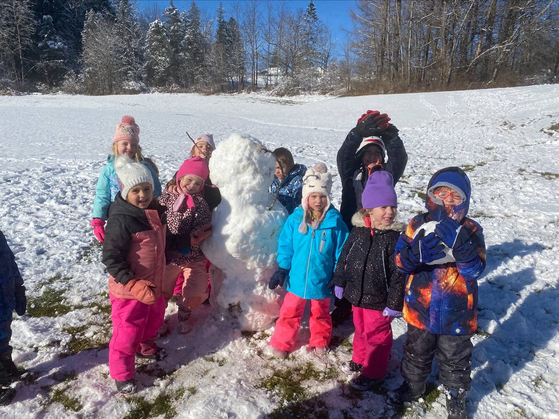a group of  students outdoors sitting on a giant snowball