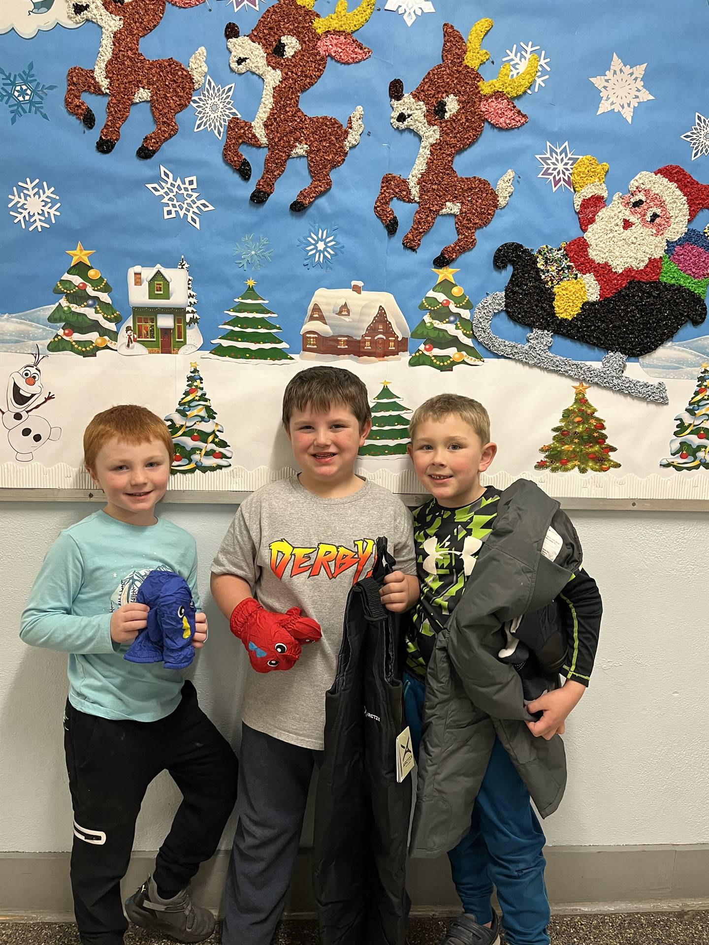 Students hold assorted winter clothing that was donated. background santa and sleigh.