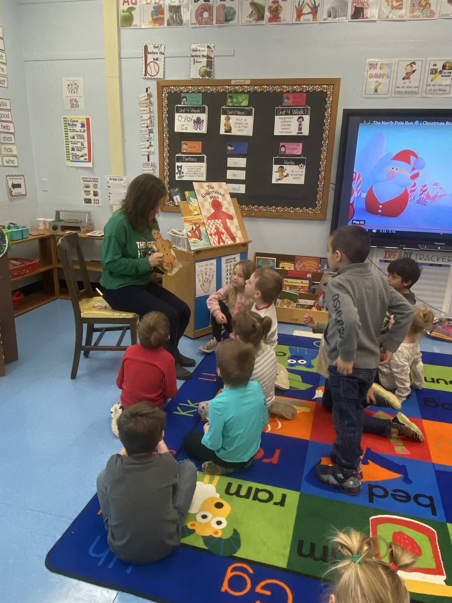 The teacher reads note from the gingerbread man while class watches.