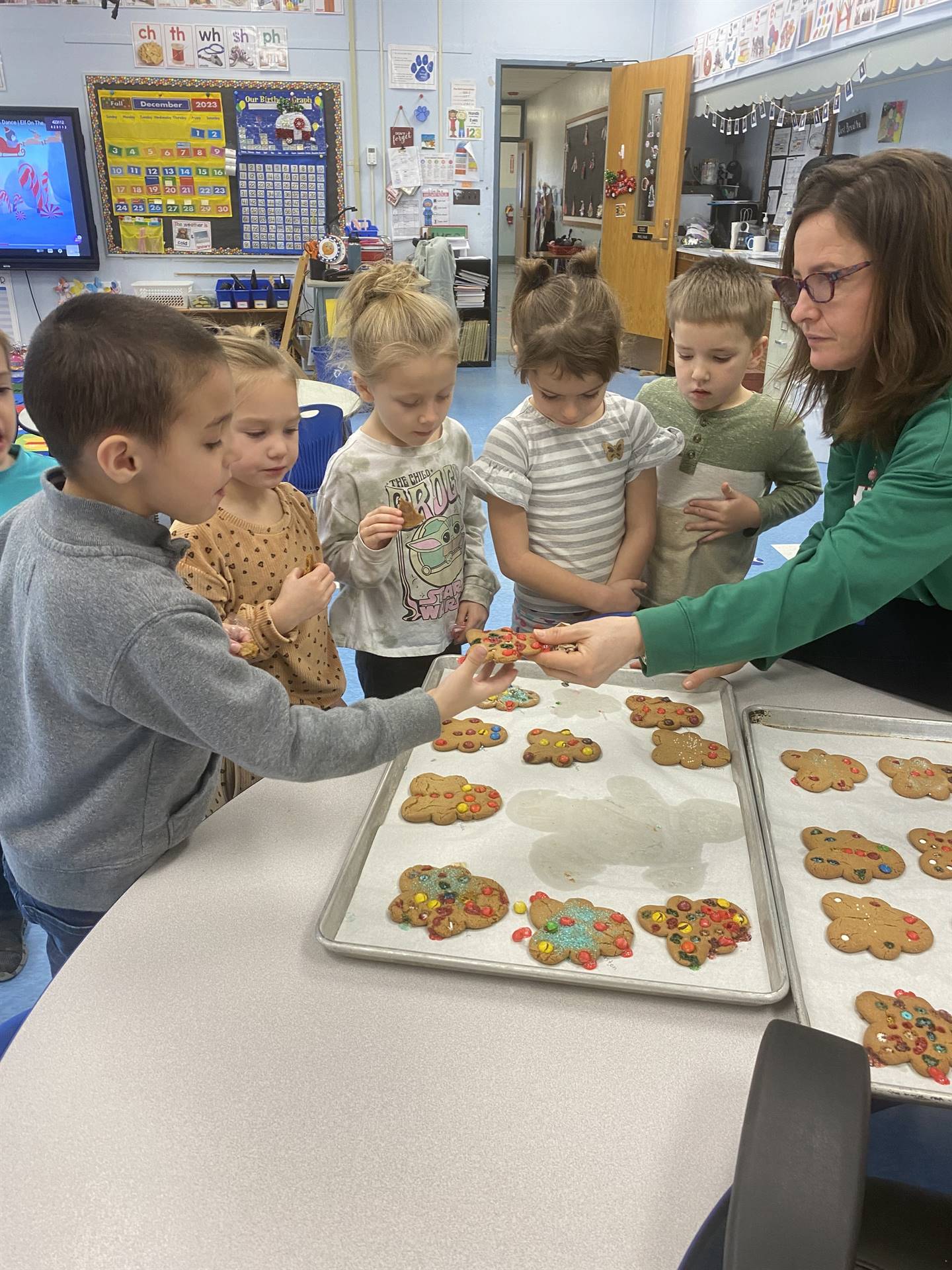 students decorating tray of gingerbread cookies.