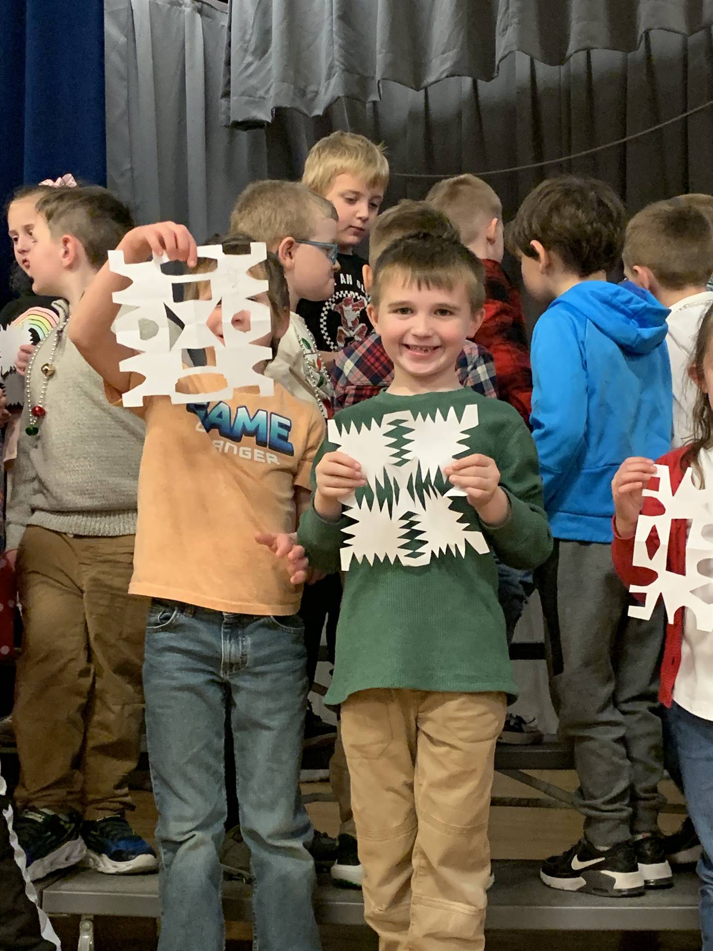 students holding paper snowflakes.