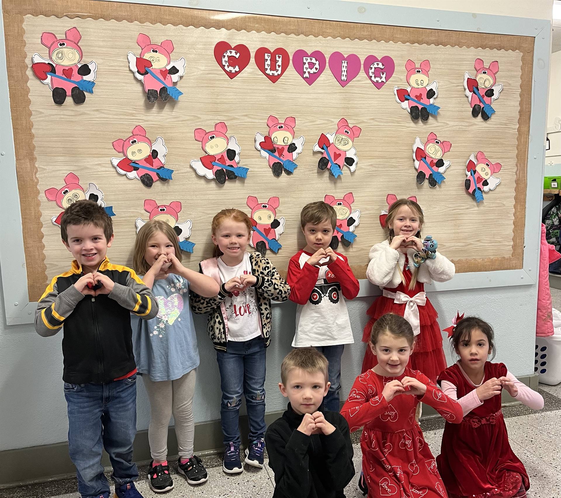 students making hearts with hands and "CUPIG" craft background.