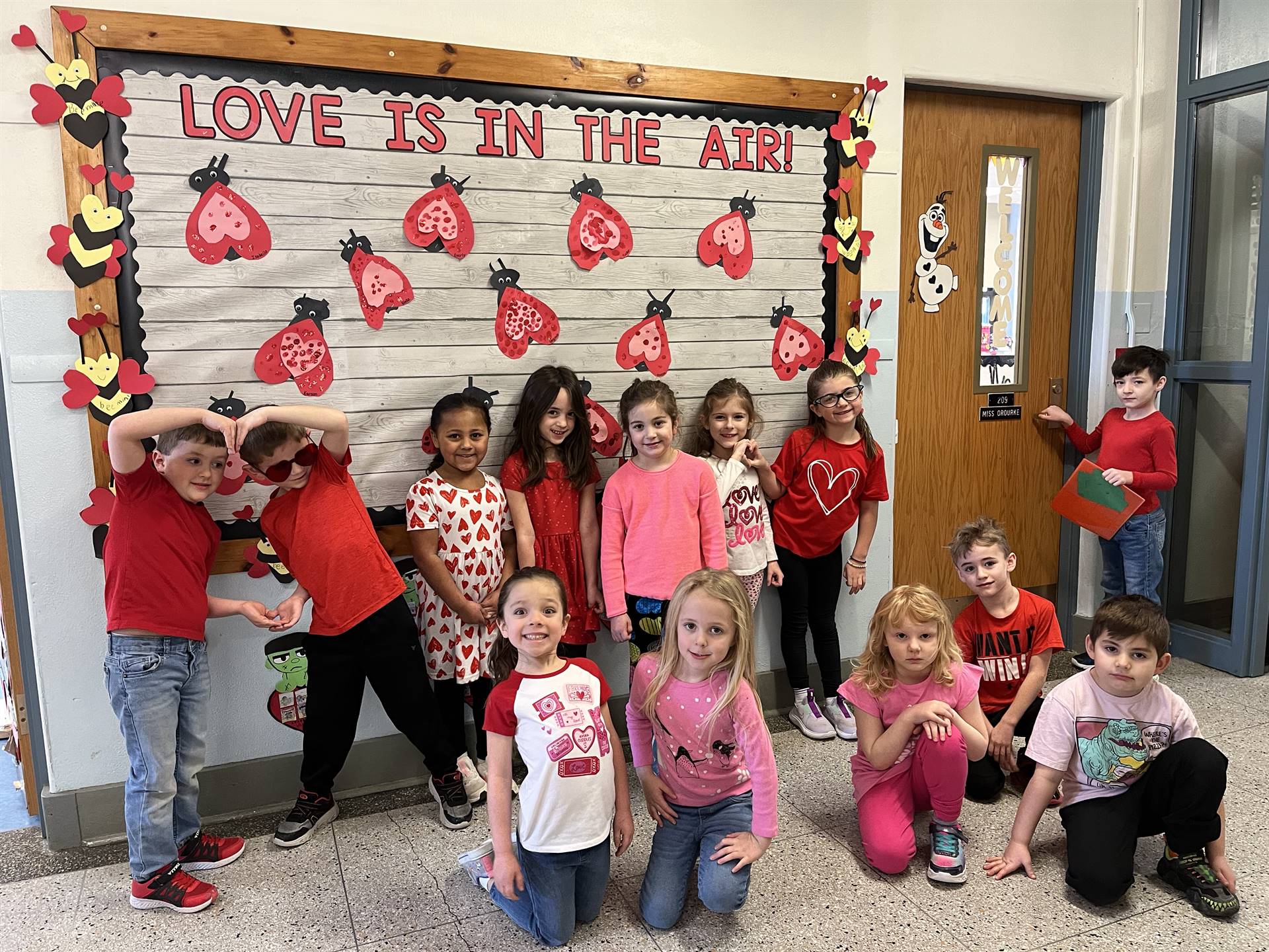 students with heart covered bulletin board in background.