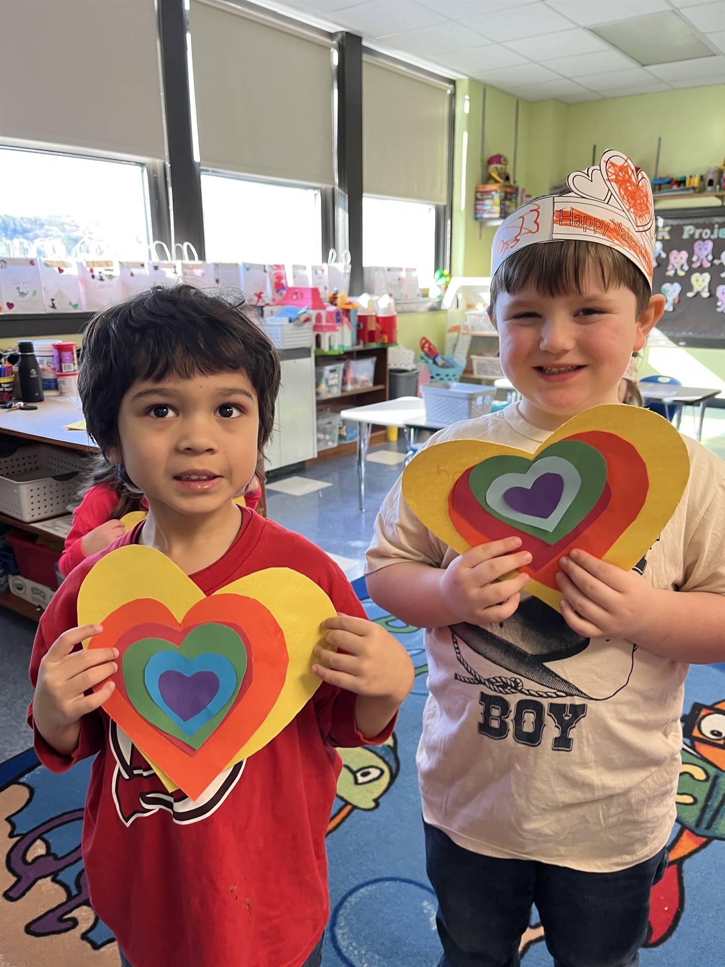 2 students holding a paper craft rainbow heart.
