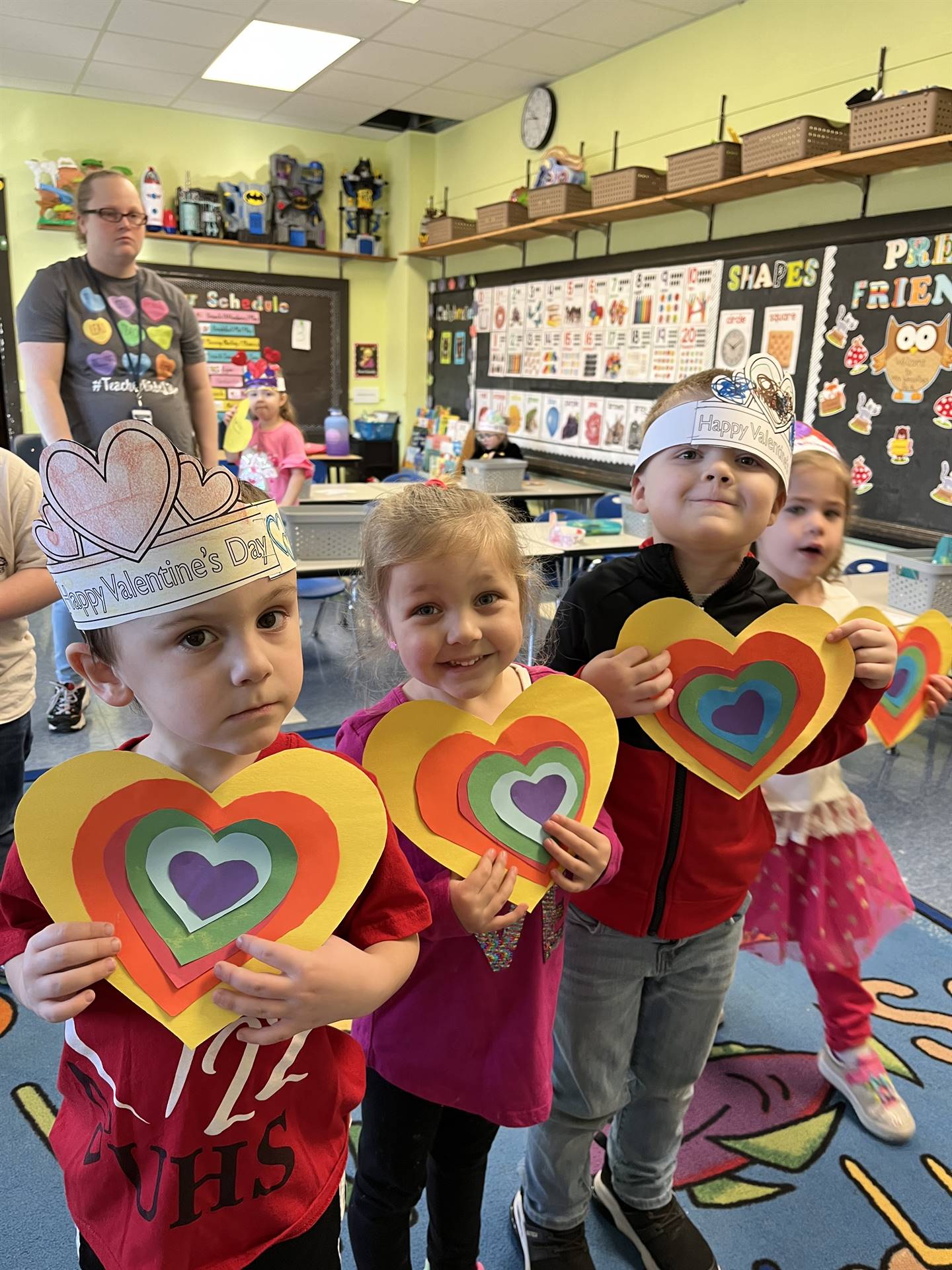 students holding a paper craft rainbow hearts.