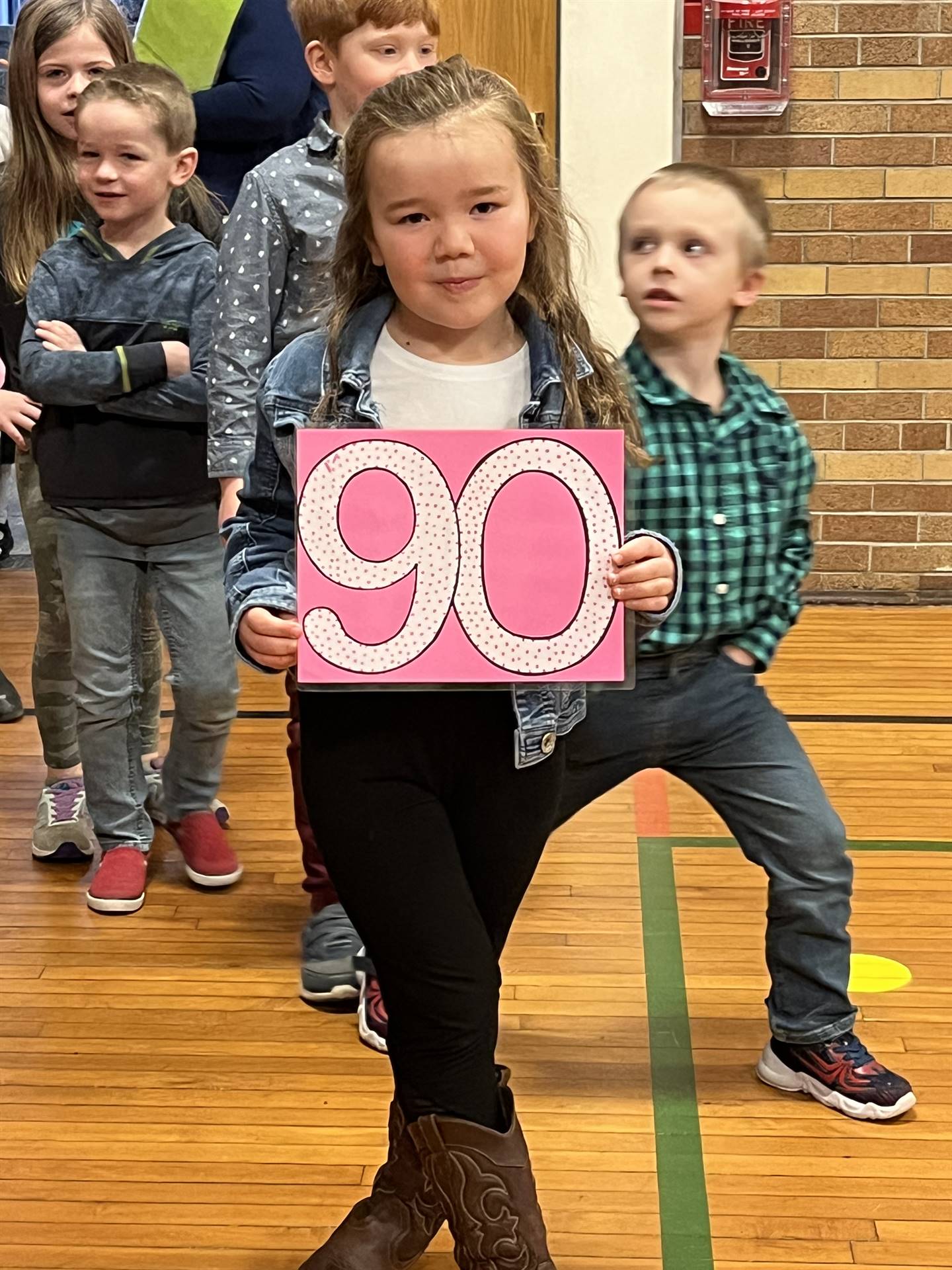a student holds a 90 sign as adults look on